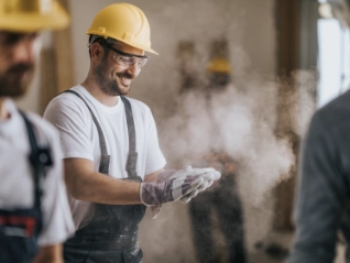 Happy construction worker with dusty gloves