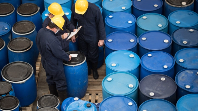 Three men inspecting chemical drums