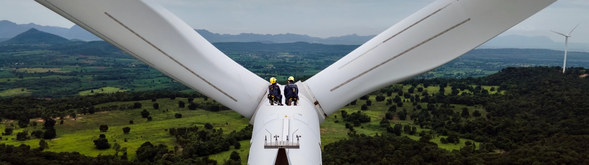 Two workers in the distance on a high level turbine