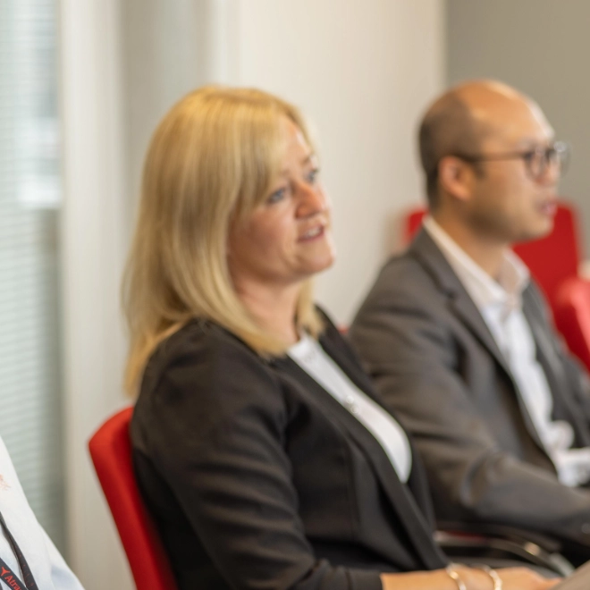 Two women and men in a large meeting room